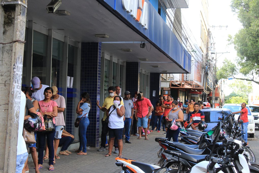 Aglomeração de pessoas em frente a bancos