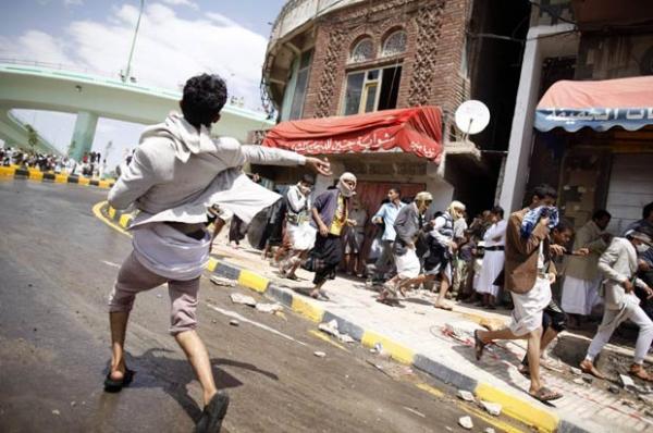 Manifestante joga pedra em policiais durante confronto próximo à embaixada dos EUA no Iêmen, em Sanaa, nesta sexta-feira (14)(Imagem:Reprodução)